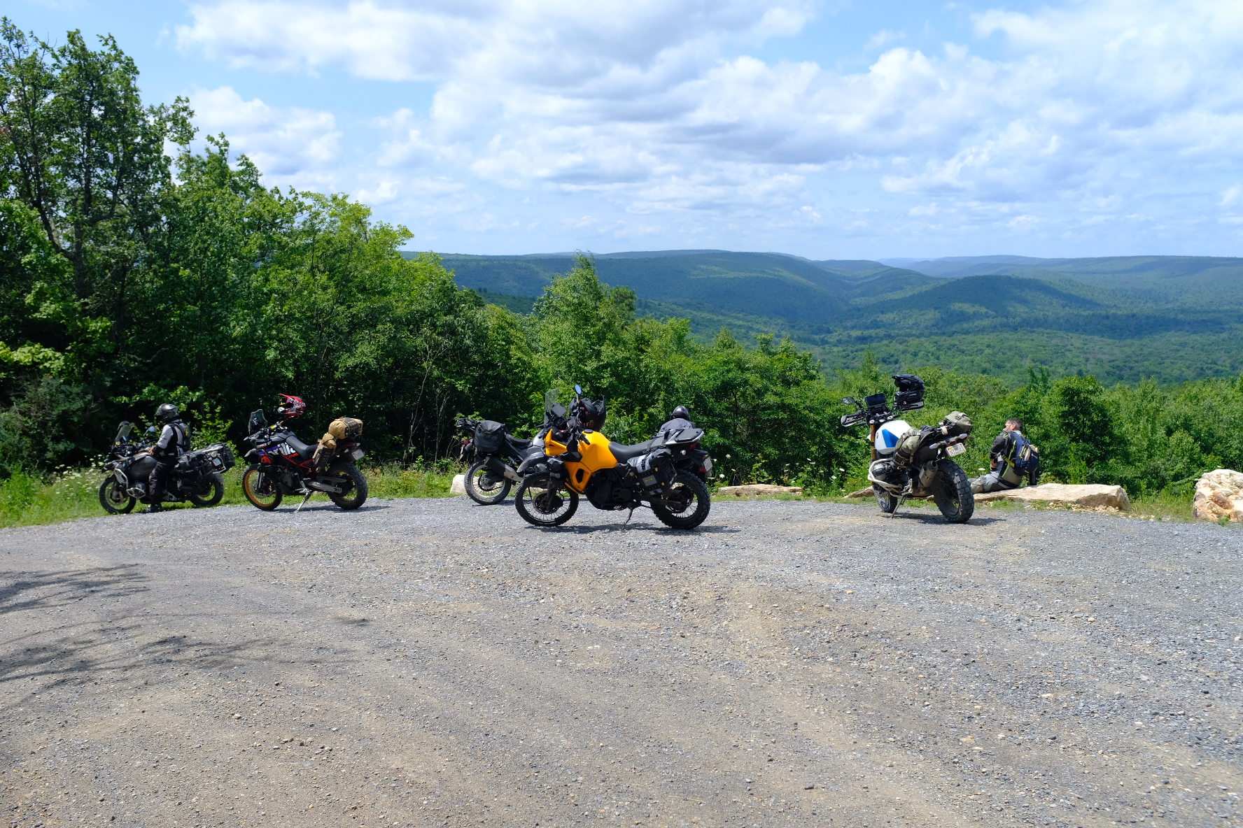 Bikes parked at a gravel overlook with rolling forested ridges in the distance