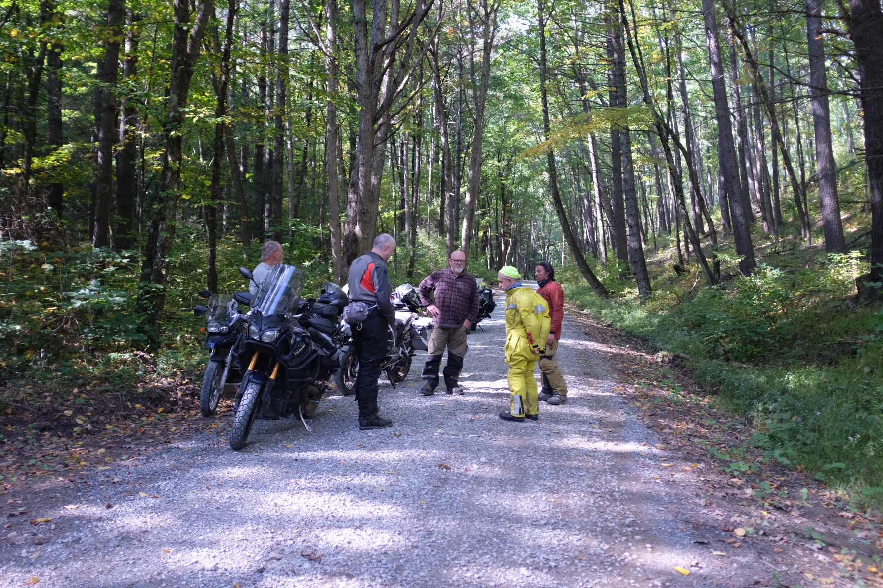Adventure riders and motorcycles regrouping on a shaded Virginia forest road