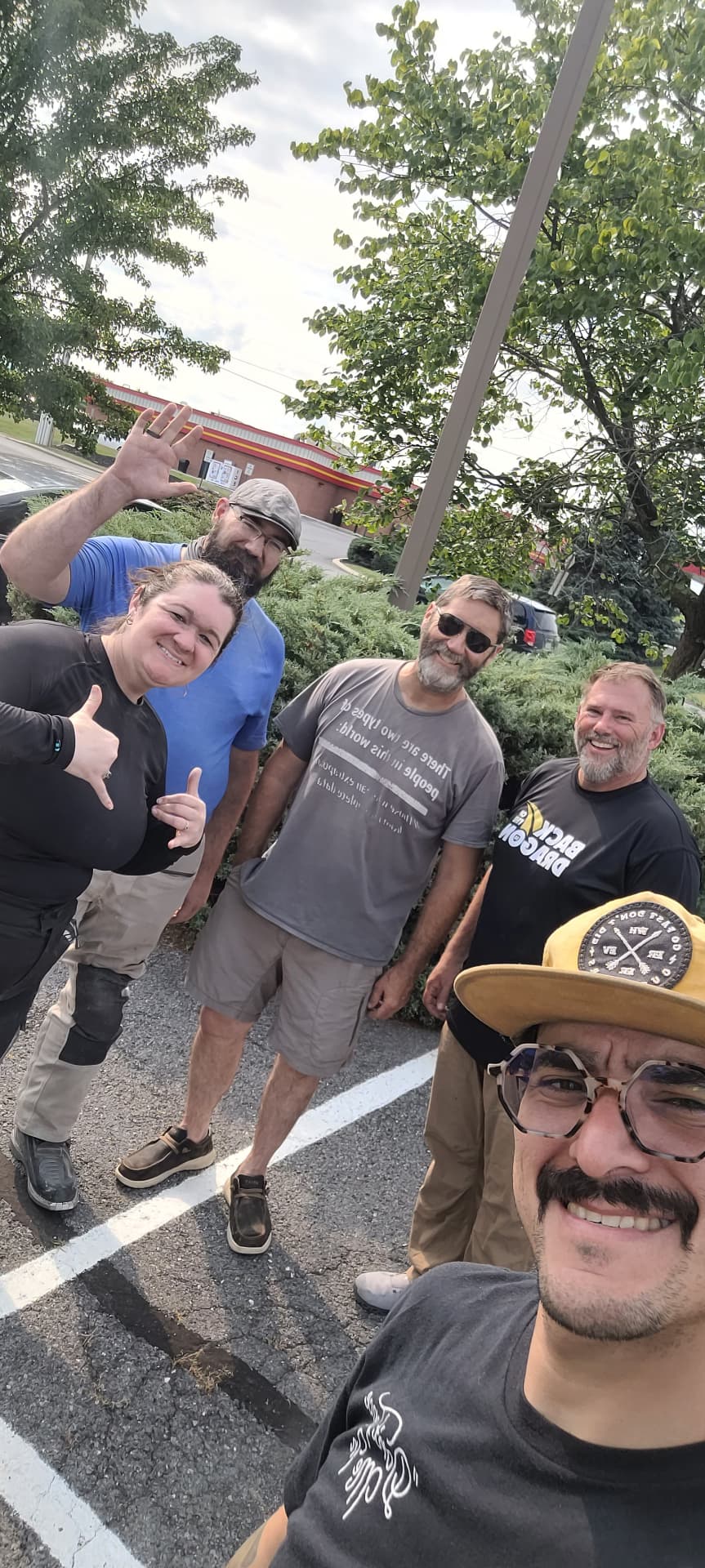 Group selfie of the riders smiling in a parking lot at the end of the trip