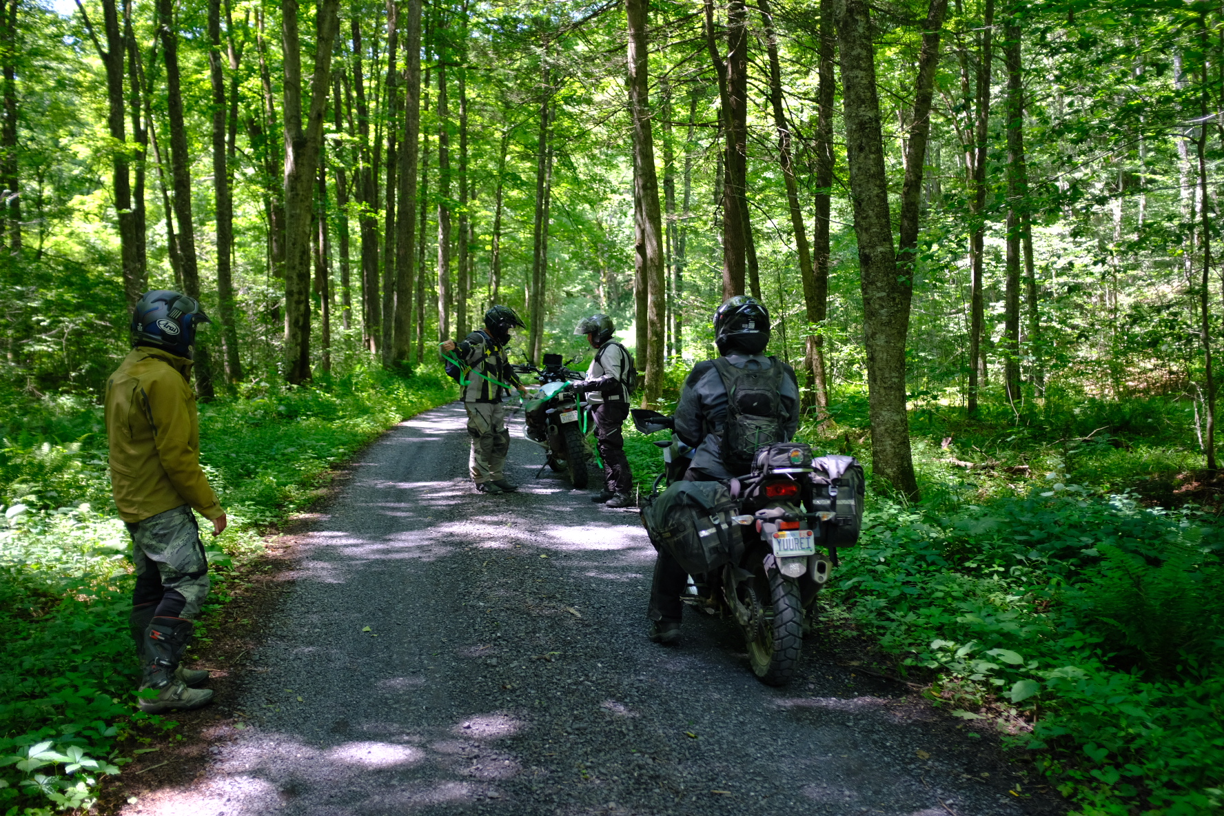 Riders rigging a tow strap on a forest road after a bike breakdown