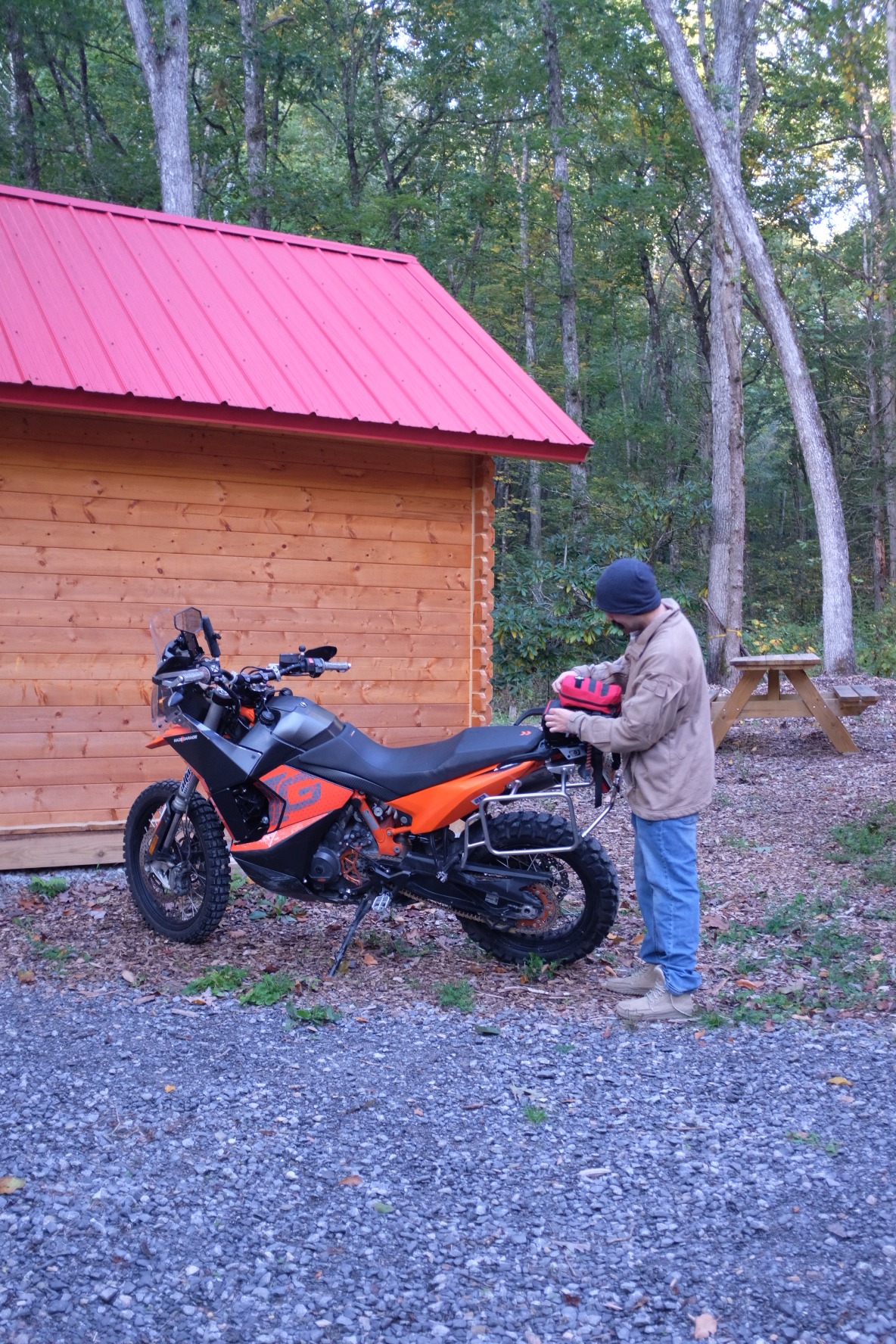 Rider preparing a KTM adventure motorcycle beside a cabin