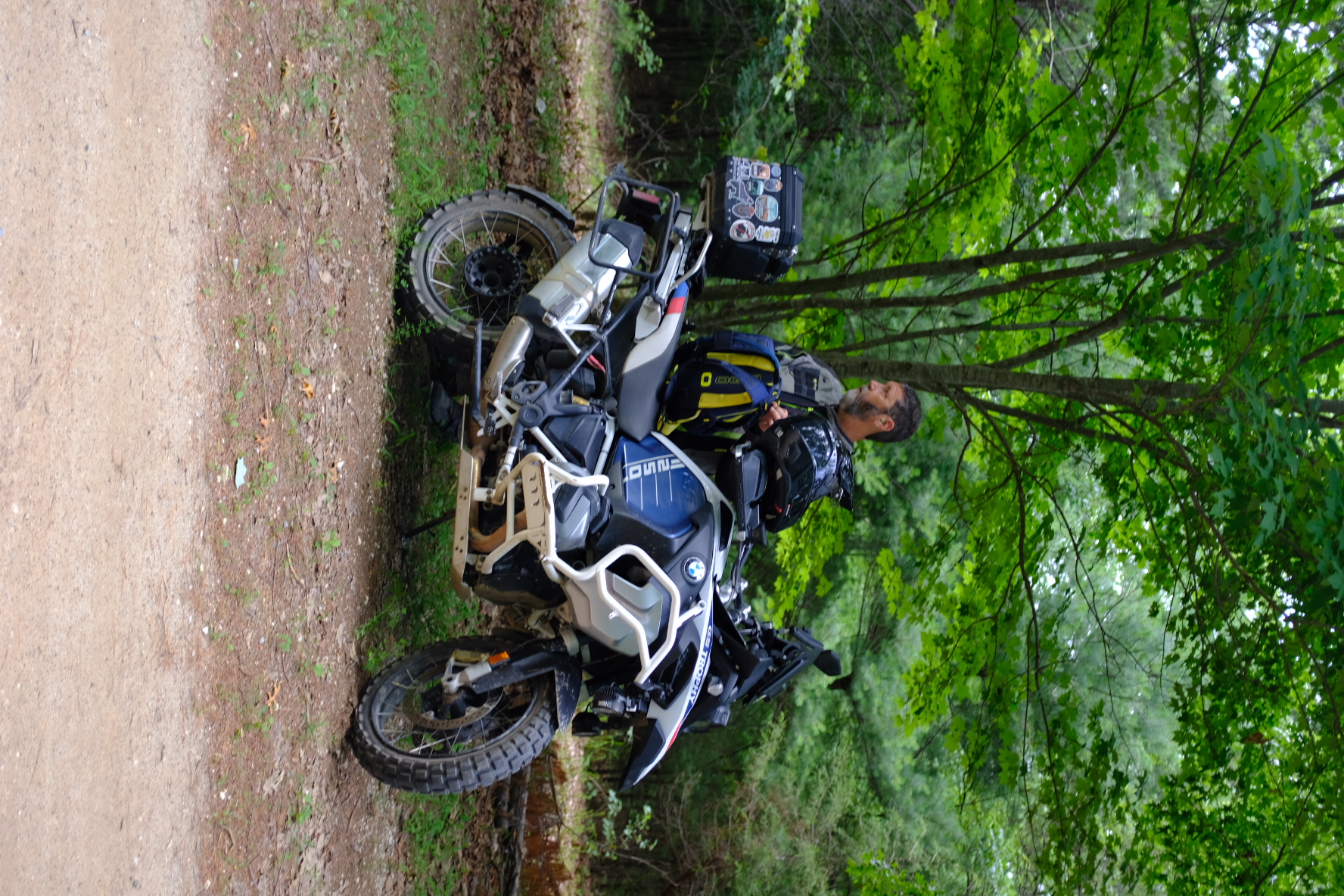 Rider standing next to a BMW R1250GS in the woods at Penmerryl Farm